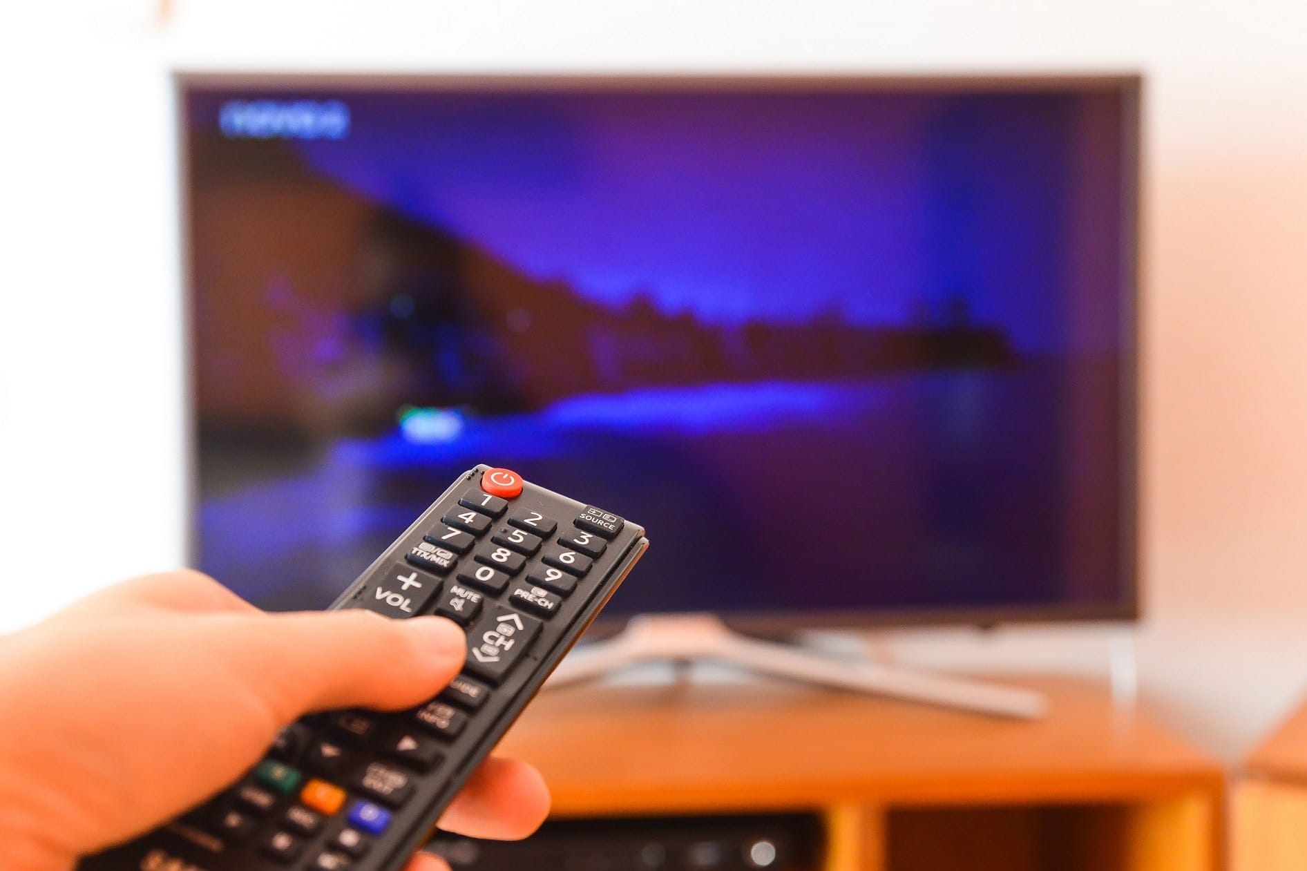 hand holding remote pointed toward television