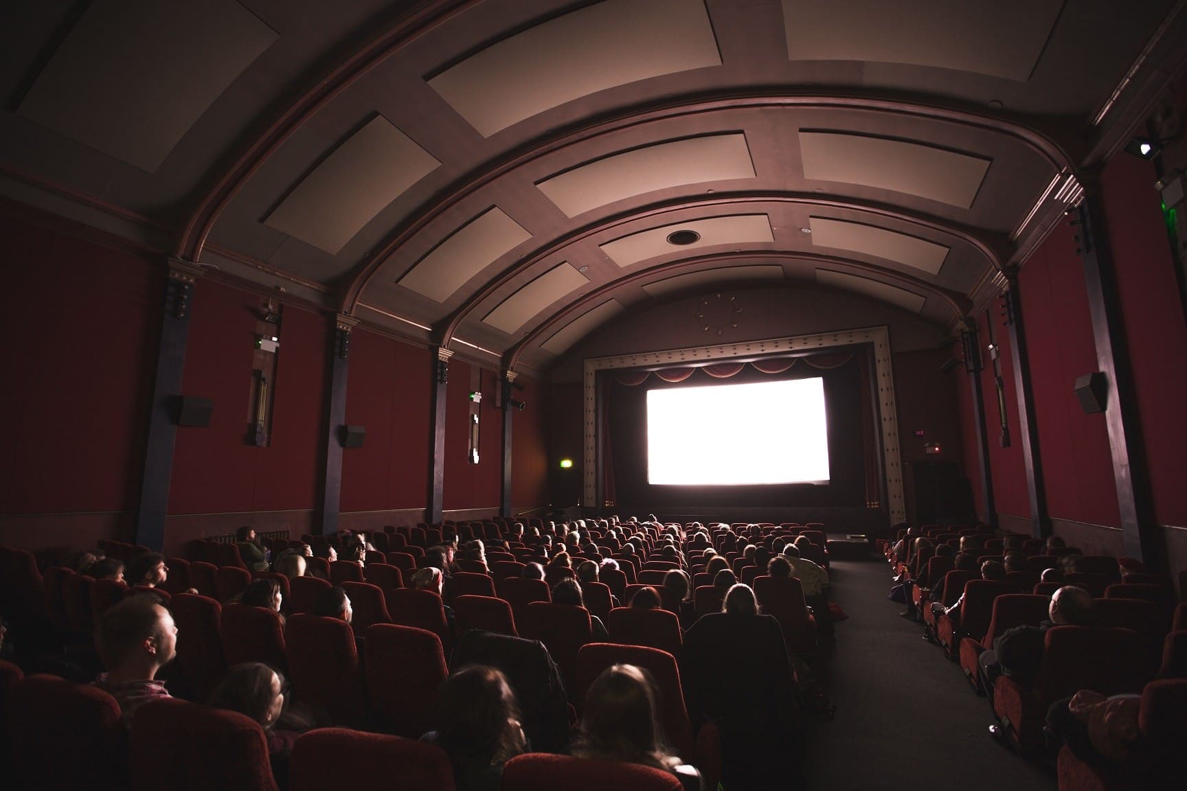 Interior of a movie theater, with audience watching a movie