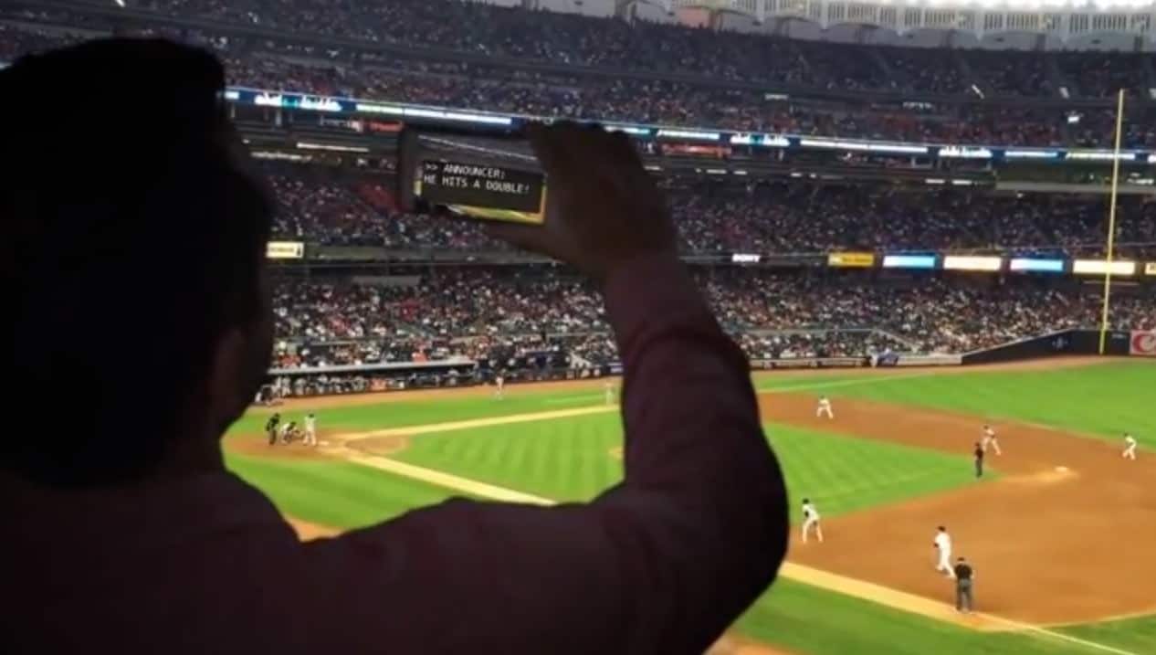 Fan reading captions from his phone at a sporting event