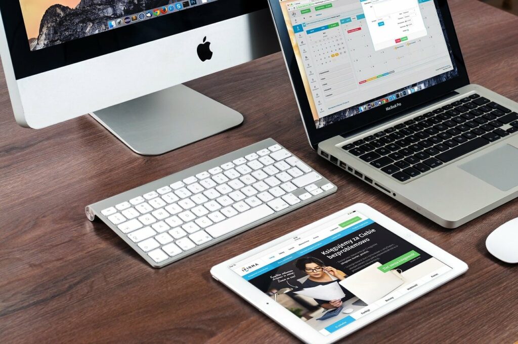 Photo of laptop, desktop, and tablet on a desk work station