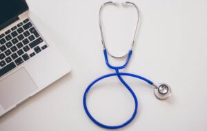A stethoscope sits on desk next to a laptop
