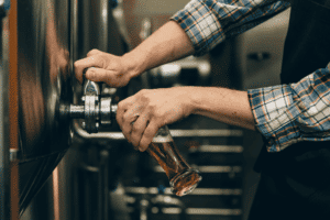 brewer pouring beer from tap