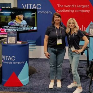 Two VITAC team members at the red and blue VITAC booth at the NAB show