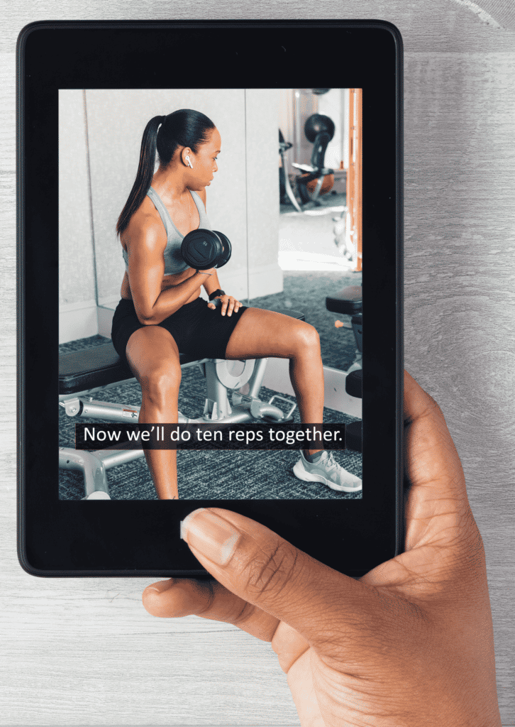 a hand holding a tablet displaying a workout video with a trainer lifting weights and the caption "Now we'll do ten reps together."