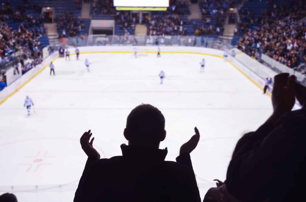 silhouettes of fans cheering on ice hockey players