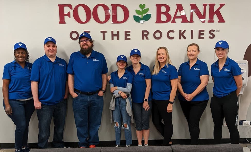 VITAC staff standing before a sign that reads Food Bank of the Rockies