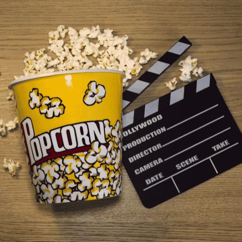 popcorn container with popcorn and movie director's clapper on a brown wooden background