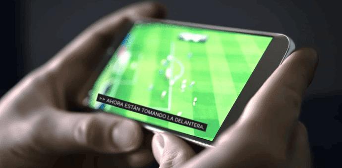 hands holding a phone with a football game playing on the screen with captions at the bottom