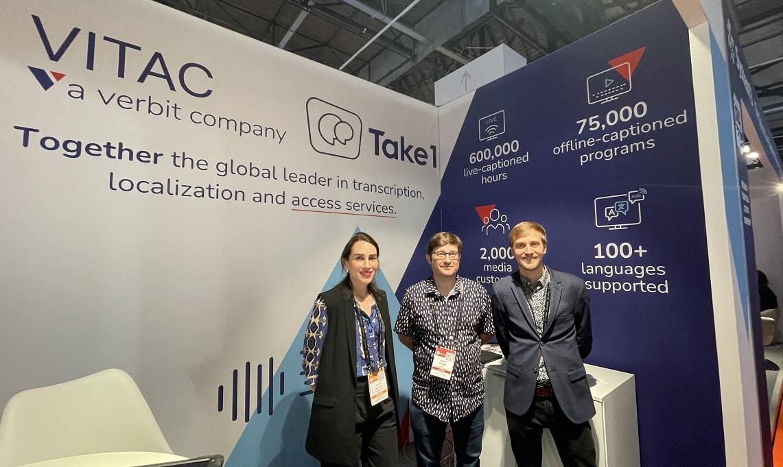 VITAC and Take 1 team members stand in front of the company booth at IBC 2022