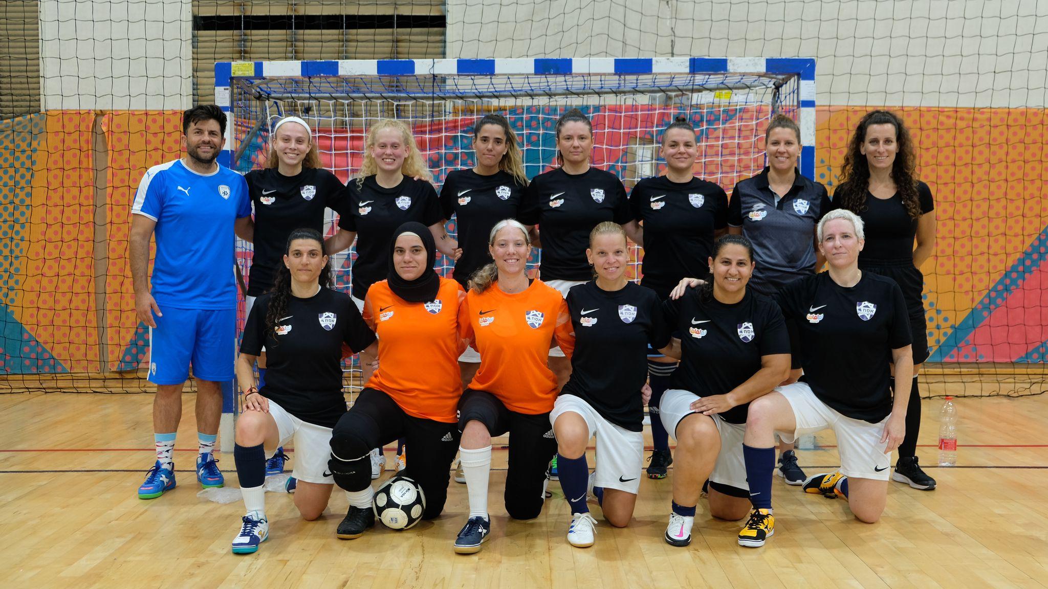 Team photo of the Israel Women’s National Futsal team with players and coaches standing in front of a futsal goal.