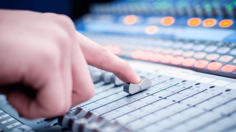 An image of a hand on a light, mixing desk fader.