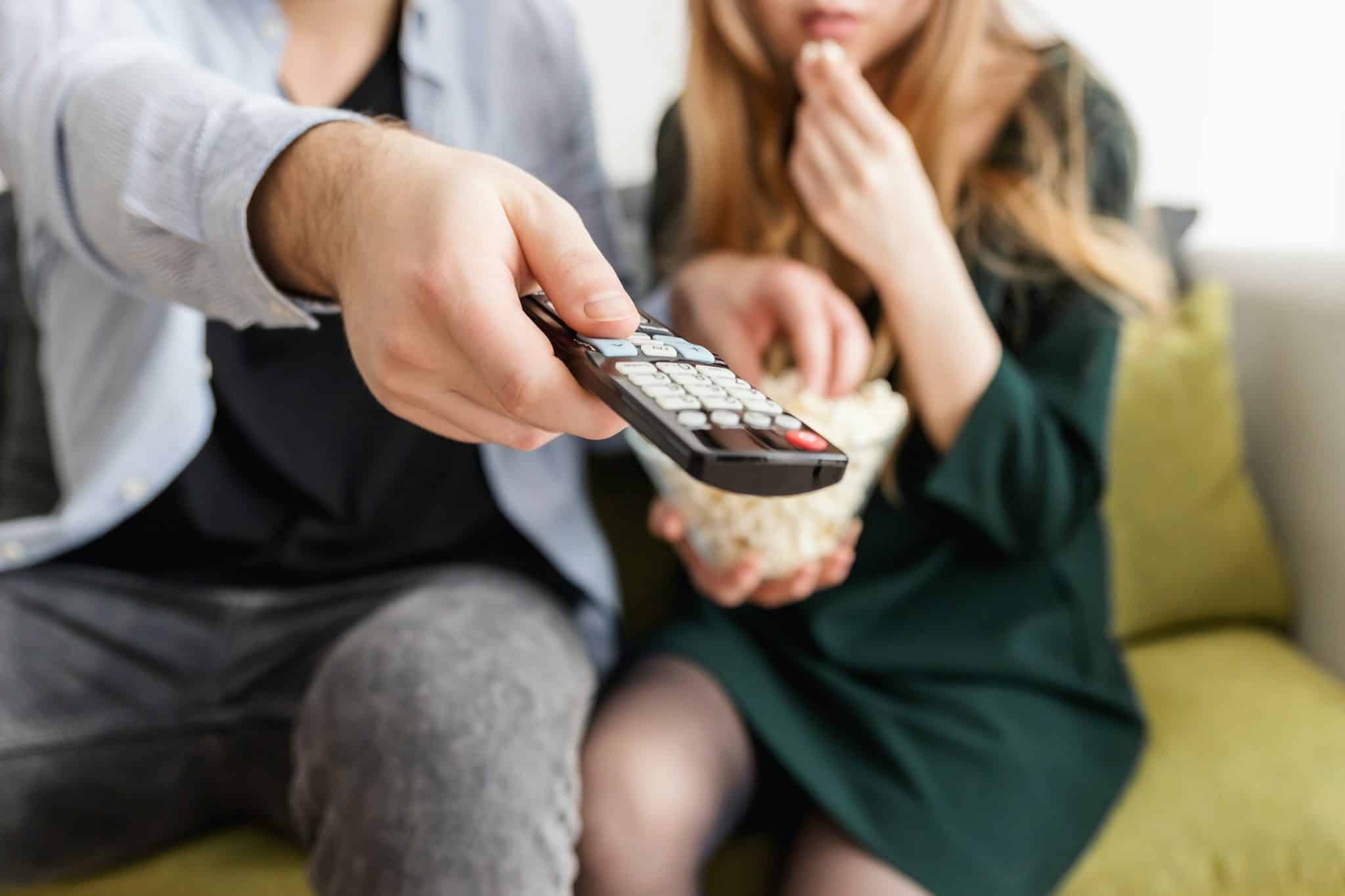 Couple using remote control to enable captions on their television