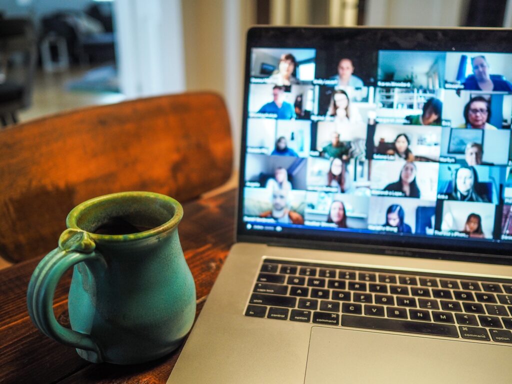 A cup of coffee sits on a table in front of an open laptop viewing a blurred image of a webinar on the screen. (for the ASR webinar blog)