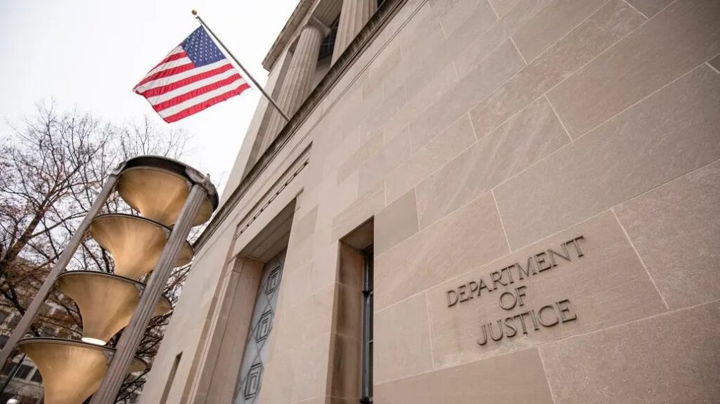 Exterior photo of the department of justice (DOJ) building with an American flag flying in front.