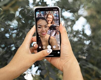image of two hands holding a phone. On the phone's screen is an Instagram Reels video featuring two young women smiling with a camera.