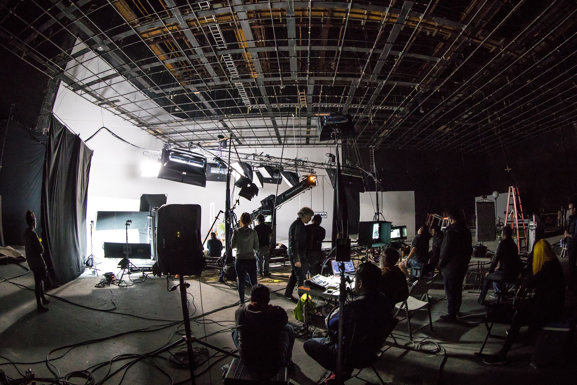 A wide shot of a movie production set with cameras, crews, and monitors inside of a large warehouse space for the Red Production blog.