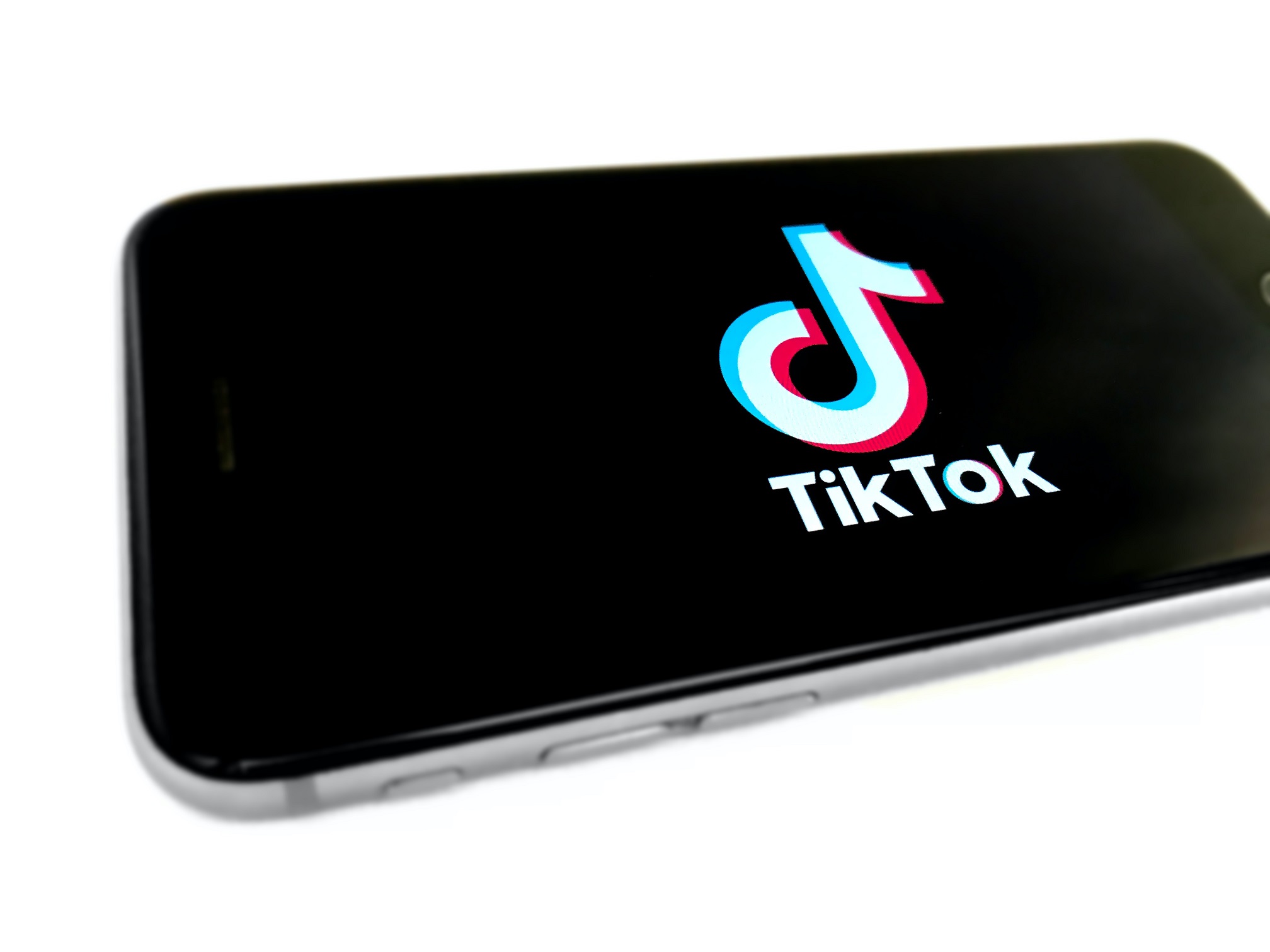The TikTok logo displayed on a cell phone with the words TikTok underneath the logo