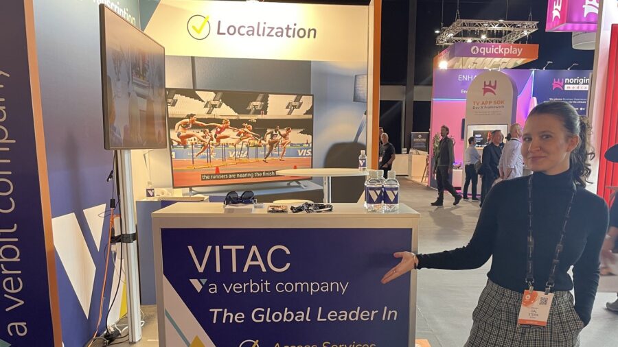 Gal Stern stands in front of the VITAC booth at IBC. The booth has the words 'the global leader in access services, transcription, and localization