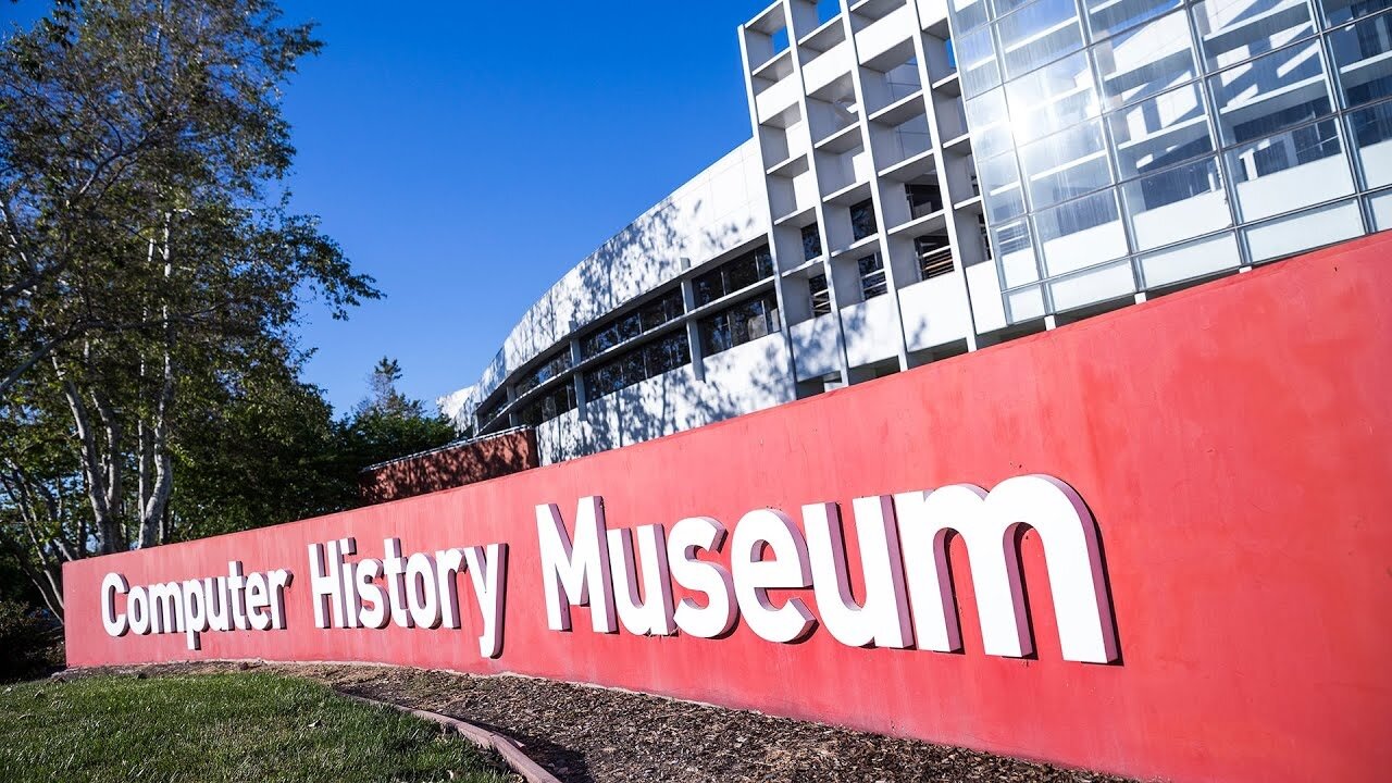 Exterior of the Computer History Museum. A red sign with white letter reading Computer History Museum stands in front of a white building