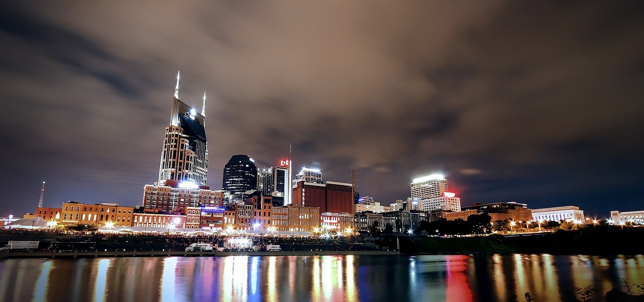The Nashville skyline pictured on the water and against a partly cloudy night sky.