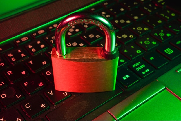 A padlock sits atop a keyboard. The scene is bathed in a strange green and red lighting.