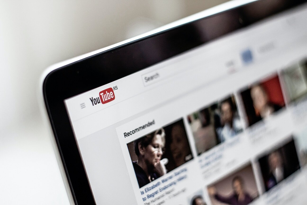 Slightly blurred image of the YouTube home screen, with thumbnail images of videos running across the top of the screen.