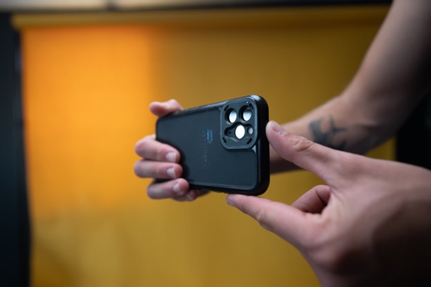 Man holding a cell phone and using the camera function to film video content