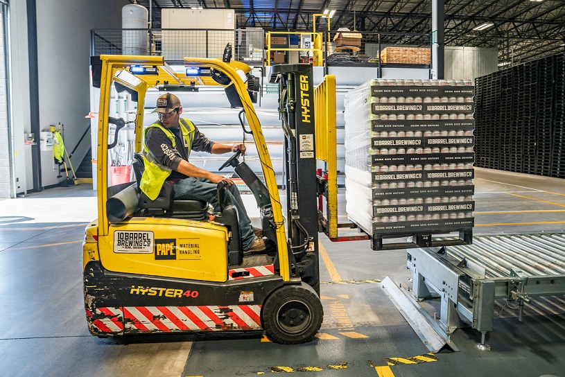 A man drives a yellow forklift in a warehouse.