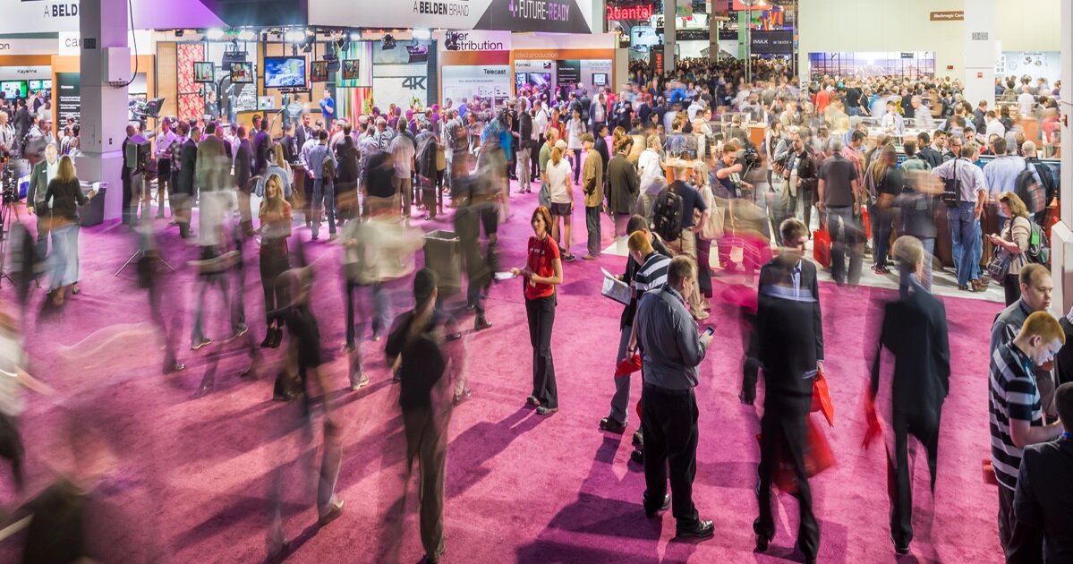 A blurred image of the NAB Show floor with people walking back and forth across the frame.