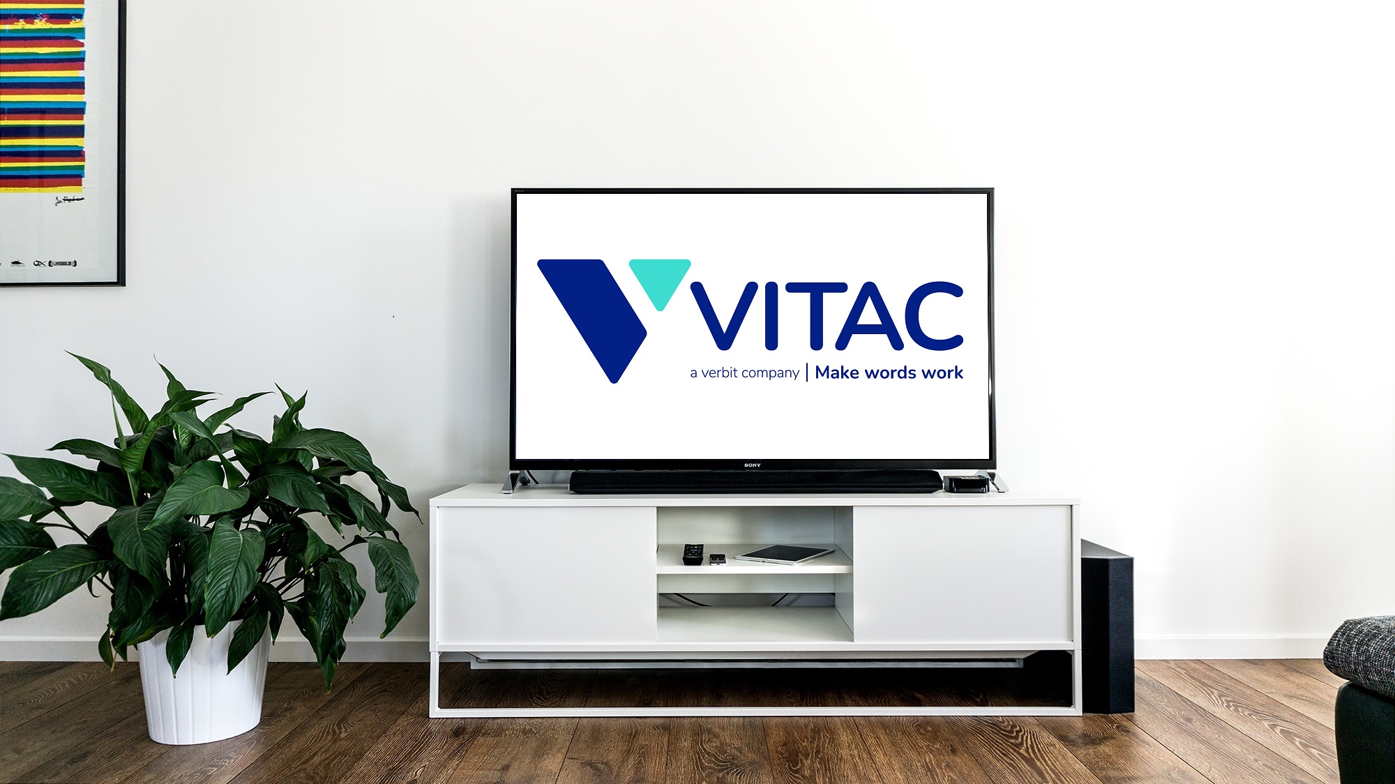 VITAC, a Verbit Company logo, on a television screen. The screen is atop a white cabinet against a white wall backdrop.