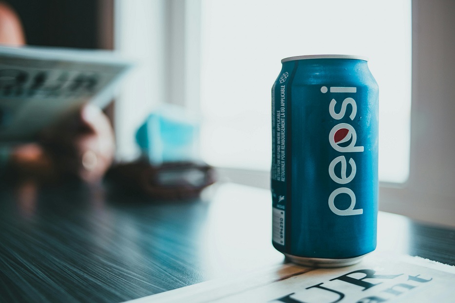 A blue can with 'Pepsi' in white letters sits on a table
