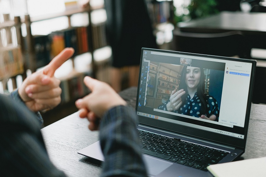 Two people communicate via sign language over a remote conference call. A woman is seen on the screen using sign language