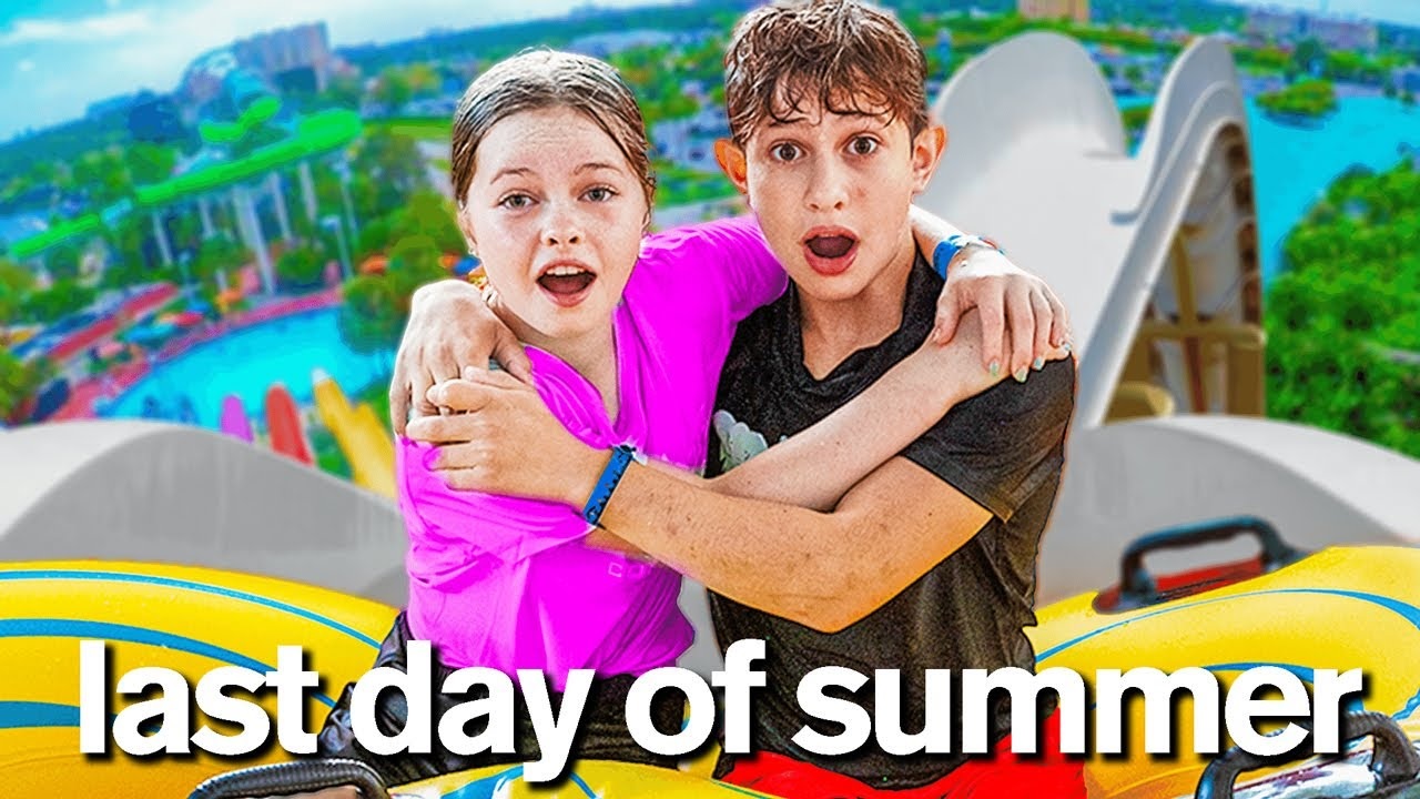 A young girl and a young boy hold each other at the top of the amusement park ride. In white letters below the image - 